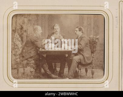 Portrait de groupe de trois hommes jouant et lisant des cartes, Carel Eduard Westerborg, photographie de 1861 - 1890. Cabinet photographie cette photo fait partie d'un album. Arnhem carton. support photographique albumen print personnes historiques anonymes dépeintes dans un groupe, dans un portrait de groupe. cartes à jouer Banque D'Images