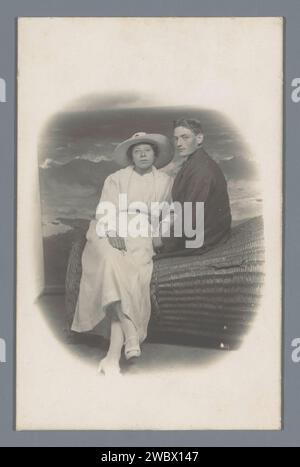 Portrait de studio d'un homme et d'une femme inconnus sur une chaise de plage en chaume, Anonyme, en ou après 1907 - c. 1920 photographie support photographique gélatine argent impression couple d'amoureux. studio  photographe Banque D'Images