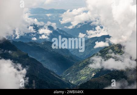 Beaux nuages de cumulus blancs sur les montagnes de l'Himalaya vallée couverte de jungles de forêt tropicale dans le parc national de Makalu Barun près de Chatra Khola colonie. Banque D'Images