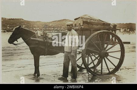 Homme avec une charrette de coquillage sur la plage, Anonyme, c. 1900 - c. 1910 photographie partie de l'album de famille avec des photos de Wijnhandel Kraaij & Co. Bordeaux-Amsterdam. véhicule photographique à deux roues, tiré par des animaux. plage Banque D'Images