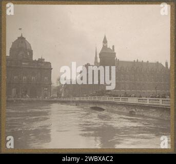 Très haut niveau d'eau dans la Seine, en arrière-plan des bâtiments sur l'Île de la Cité van Paris, G. Dangeux, 1910 photographie à droite le ferry au change, l'arc presque invisible à cause du haut niveau d'eau. En arrière-plan à droite la conciergerie sur le Quai de l'Hoogle, à gauche le Tribunal de Commerce de Paris sur le Quai de la Corse. Fait partie de l'album photo Flooding Paris and Suburbs 1910. Inondation de support photographique de Paris (+ paysage avec figures, staffage). pont. tour, tour de l'horloge  ornement monumental. Dôme  architecture City Island Banque D'Images