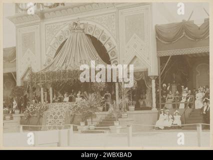 Festivités sur le site de l'IJsclub à Amsterdam a l'occasion de l'inauguration de la reine Wilhelmina, 1898 photo assise sous une verrière, la mère Koningin Emma, la princesse Wilhelmina et des dignitaires vivent des festivités sur le site de l'IJsclub (aujourd'hui Museumplein), la veille de l'inauguration de la princesse. Partie de l'album photo avec 11 enregistrements de l'inauguration de la reine Wilhelmina et les fêtes d'inauguration. Carton carré musée. papier. Support photographique installation d'une règle - BB - règle femelle. célébration cérémonielle de l'installation d'une règle. public f Banque D'Images