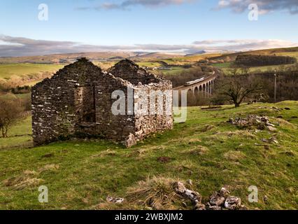 Une vue du viaduc Smardale sur le chemin de fer Settle-Carlisle, près de Crosby Garrett, Cumbria, avec une grange agricole en pierre en ruine au premier plan. Banque D'Images