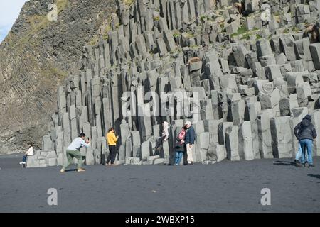 Touristes posant pour des photos sur les colonnes basaltiques de Reynisfjall, une montagne de tuf de 340 mètres de haut près de la ville de Vik, Islande Banque D'Images