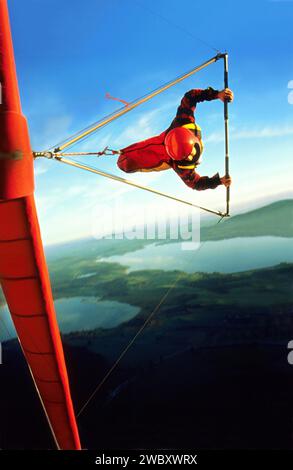 Pilote de deltaplane avec hangglider rouge et casque rouge dans une courbe raide, également appelé vol au couteau, au-dessus de Fuessen Allgaeu Bavière Allemagne Banque D'Images