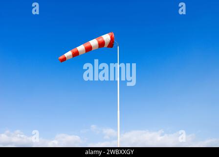 chaussette de vent dans le ciel bleu, rouge et blanc, indiquant un vent modéré Banque D'Images