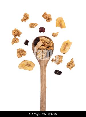 granola croquant dans une cuillère en bois isolé sur fond blanc avec chemin de coupe, pile de muesli avec des noix, canneberges et raisins secs, petit déjeuner sain Banque D'Images