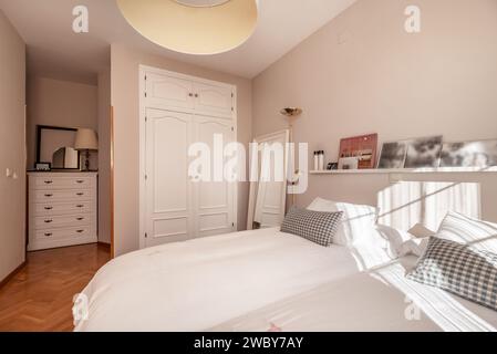 Une chambre dans une maison unifamiliale de différentes hauteurs avec armoires en bois blanc intégrées et meubles assortis Banque D'Images