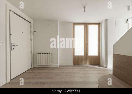 Hall d'une maison avec murs peints en blanc lisse, portes coulissantes en bois et en verre opaque et parquet en chêne Banque D'Images