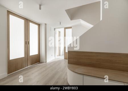 Hall d'une maison avec murs peints en blanc lisse, portes coulissantes en bois et en verre opaque et parquet en chêne Banque D'Images