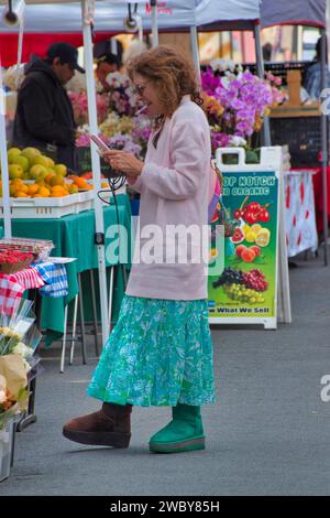 Carmel, Californie, États-Unis - 14 décembre 2023 une femme vérifie sa liste de courses au marché hebdomadaire des fermiers/de rue de CarmelÕs sur la 6e rue par Devendorf Park Banque D'Images