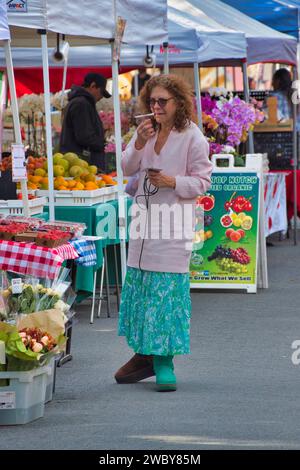 Carmel, Californie, États-Unis - 14 décembre 2023 une femme vérifie sa liste de courses au marché hebdomadaire des fermiers/de rue de CarmelÕs sur la 6e rue par Devendorf Park Banque D'Images