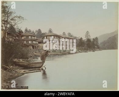 Maisons et un pêcheur sur le lac Chuzenji à Nikko, Anonyme, c. 1870 - c. 1900 photographie partie de Reisalbum avec des photos de sites au Japon. Nikko carton. papier. laque photographique pour impression à l'albumine. Angling Nikko Banque D'Images