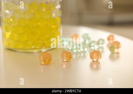 Différentes couleurs de remplissage et vase en verre sur table blanche dans la chambre, gros plan. Perles d'eau Banque D'Images