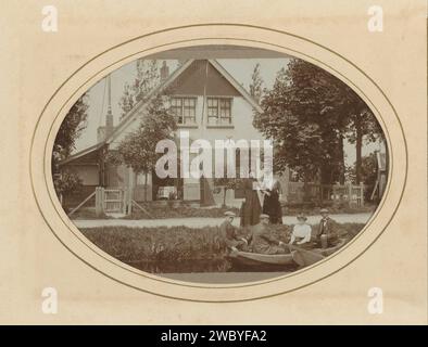 Trois hommes et une femme dans un bateau à rames et deux femmes à terre, avec une maison en arrière-plan, A.W. van Leeuwen, photographie de 1883 - 1904. Cabinet photographie cette photo fait partie d'un album. Carton Nieuwveen. support photographique homme adulte (+ trois personnes). femme adulte (+ trois personnes). bateau à rames, canoë, etc. architecture civique ; édifices ; habitations Banque D'Images