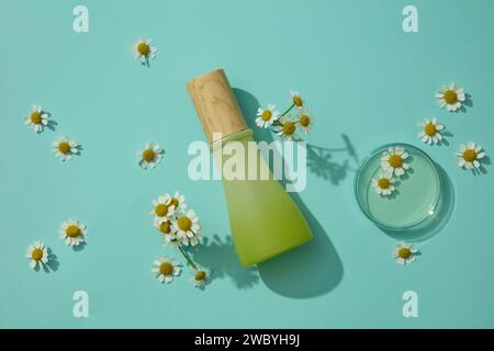 Vue du dessus de la bouteille cosmétique exposée avec une boîte de Petri en verre contenant un liquide transparent avec des fleurs fraîches. Cosmétiques, produits de soins et p Banque D'Images