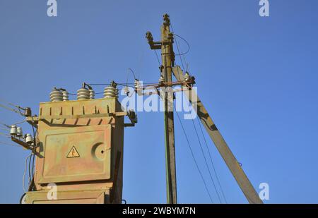 Vieux et obsolètes de transformateur électrique dans le contexte d'un ciel bleu. Dispositif pour la distribution de fourniture de l'énergie à haute tension Banque D'Images