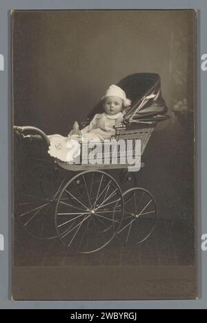 Portrait en studio d'un bébé dans une poussette, W.F. Pastor, c. 1910 - c. 1925 photographie. Photographie de cabinet Loppersum carton. support photographique gélatine argentique voiture d'enfant, poussette, voiture d'enfant. bébé, bébé Banque D'Images