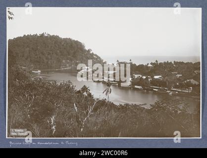 Vue de la Handelskade à Padang avec des navires, des hangars et des maisons, Christiaan Benjamin Nieuwenhuis, c. 1900 - c. 1920 photographie partie de Reisalbum avec des photos des activités et des sites sur Sumatra et Java et du voyage vers et des Indes orientales néerlandaises. Papier padang. support photographique gélatine argentique port (+ vue  véhicule, navire, etc.). perspective de ville, panorama de ville, silhouette de ville. Entrepôt ( port) Padang Banque D'Images