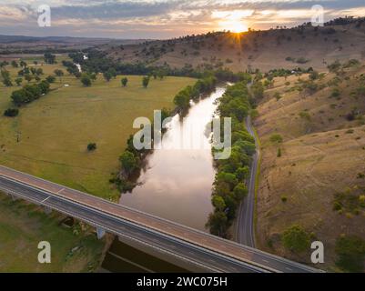 Vue aérienne du coucher de soleil sur les collines entourant une rivière qui coule à travers les terres agricoles à Gundagai en Nouvelle-Galles du Sud, Australie Banque D'Images
