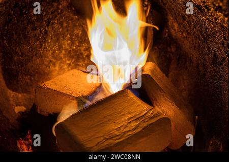 Briquettes de bois (type ruf), en hêtre et chêne brûlant à l'intérieur de la chaudière à bois. Carburant alternatif, éco-carburant, bio-carburant. Banque D'Images