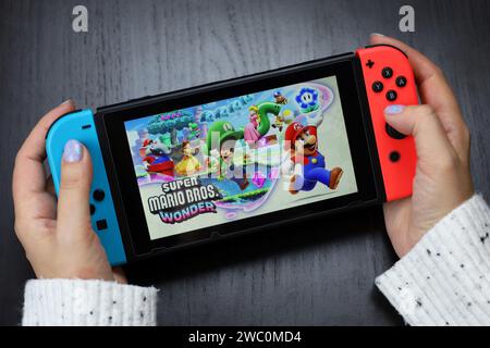 Fille jouant Super Mario Bros. Wonder jeu sur console Nintendo Switch en mode portable Banque D'Images