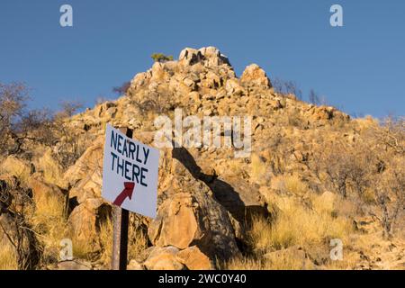 Un panneau fait à la main indique presque là sur un sentier pédestre dans les collines namibiennes près des rochers Erongo dans le nord de la Namibie Banque D'Images