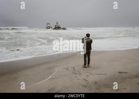 Un touriste prend une photo de l'un des naufrages sur la Skeleton Coast en Namibie Banque D'Images