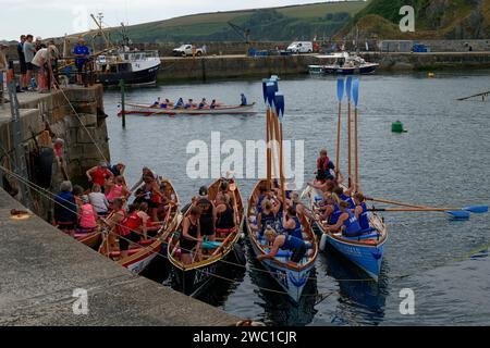 Les équipages se préparent sur leurs bateaux pour les dames pilote gig course à la régate, Mevagissey, Cornouailles, Angleterre, Royaume-Uni Banque D'Images