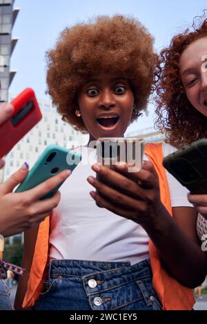 Image verticale d'une jeune femme africaine regardant un téléphone portable surpris. Banque D'Images