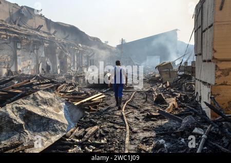 Homme à l'intérieur du complexe industriel brûlé. Usine endommagée et détruite. Restes de bâtiment brûlé. Dommages causés par le feu. Halls industriels endommagés Banque D'Images