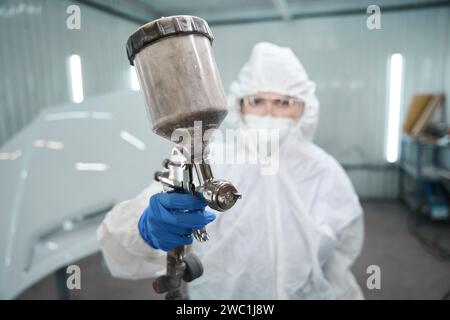 Maître de peinture avec un réservoir d'injection de peinture dans ses mains Banque D'Images