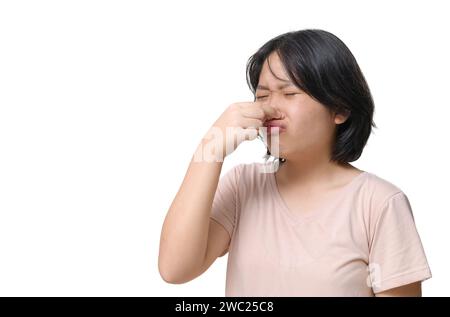 Jolie fille portant un T-shirt rose couvre son nez avec sa main parce qu'il sent mauvais. fond blanc Banque D'Images