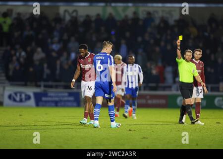 L'arbitre Anthony Backhouse montre un carton jaune à Charlie Hughes de Wigan Athletic lors de la seconde moitié du match de Sky Bet League 1 entre Northampton Town et Wigan Athletic au PTS Academy Stadium, Northampton le samedi 13 janvier 2024. (Photo : John Cripps | MI News) crédit : MI News & Sport / Alamy Live News Banque D'Images