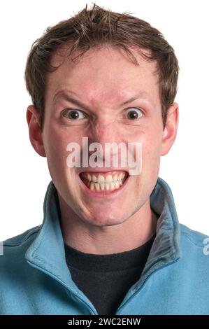 Portrait de tête frontale d'un jeune homme caucasien brunette avec un regard en colère à la caméra et montrant des dents isolées sur blanc. Banque D'Images