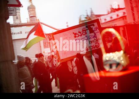 Spiegelung der Demo im Schaufenster. AM 13.01.2024 versammelten sich erneut Hunderte Menschen, UM für einen sofortigen Waffenstillstand im sog. Nah-Ost-Konflikt zu demonstrieren und UM ihre Solidarität mit Palästina zu zeigen. SIE trauerten UM die Toten in Palästina und forderten Frieden für Gaza und einen Stopp des Krieges. -- réflexion de la démo dans une vitrine. Le 13 janvier 2024, des centaines de personnes se sont rassemblées à Munich, en Allemagne, pour protester pour un cessez-le-feu immédiat au Moyen-Orient et pour montrer leur solidarité avec les Palestiniens. Ils ont pleuré les victimes en Palestine, appelé à la paix pour gaz Banque D'Images