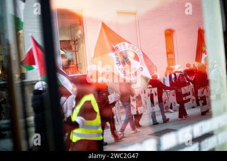 Spiegelung der Demo im Schaufenster. AM 13.01.2024 versammelten sich erneut Hunderte Menschen, UM für einen sofortigen Waffenstillstand im sog. Nah-Ost-Konflikt zu demonstrieren und UM ihre Solidarität mit Palästina zu zeigen. SIE trauerten UM die Toten in Palästina und forderten Frieden für Gaza und einen Stopp des Krieges. -- réflexion de la démo dans une vitrine. Le 13 janvier 2024, des centaines de personnes se sont rassemblées à Munich, en Allemagne, pour protester pour un cessez-le-feu immédiat au Moyen-Orient et pour montrer leur solidarité avec les Palestiniens. Ils ont pleuré les victimes en Palestine, appelé à la paix pour gaz Banque D'Images