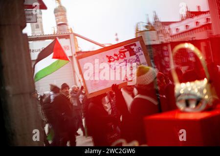 Spiegelung der Demo im Schaufenster. AM 13.01.2024 versammelten sich erneut Hunderte Menschen, UM für einen sofortigen Waffenstillstand im sog. Nah-Ost-Konflikt zu demonstrieren und UM ihre Solidarität mit Palästina zu zeigen. SIE trauerten UM die Toten in Palästina und forderten Frieden für Gaza und einen Stopp des Krieges. -- réflexion de la démo dans une vitrine. Le 13 janvier 2024, des centaines de personnes se sont rassemblées à Munich, en Allemagne, pour protester pour un cessez-le-feu immédiat au Moyen-Orient et pour montrer leur solidarité avec les Palestiniens. Ils ont pleuré les victimes en Palestine, appelé à la paix pour gaz Banque D'Images