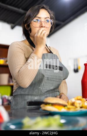 jeune femme mangeant à l'intérieur du restaurant avec des frites, portrait de style de vie et de beauté, occupation de chef, régime alimentaire malsain Banque D'Images