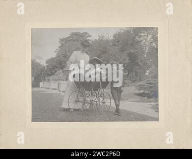 Portrait d'une femme avec deux enfants, anonyme, 1900 - 1915 photographie l'un des enfants est dans une voiture d'enfant, l'autre est appuyé sur l'Ekinderagen. La société est dans un parc inconnu support photographique impression d'argent gélatine Banque D'Images