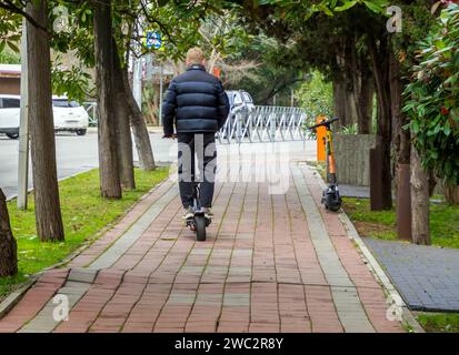 Sotchi, Russie - 2023 février 23 : un homme longe le trottoir sur un scooter électrique loué Banque D'Images