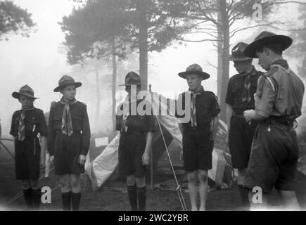 1941, historique, soleil blanc et un matin brumeux tôt dans un camp de scouts à Broadstone, Poole, Dorset, avec une inspection de troupe de courlis ayant lieu. Brownsea Island, également près de Poole, était en 1907, l'endroit où le fondateur du mouvement scout, officier de l'armée britannique, Robert Baden-Powell, a créé son camp d'essai pour les garçons et l'année suivante a publié son célèbre livre, Scouting for Boys. Deux ans plus tard, avec sa sœur, Agnès, Baden-Powell fonde les Guides. Banque D'Images