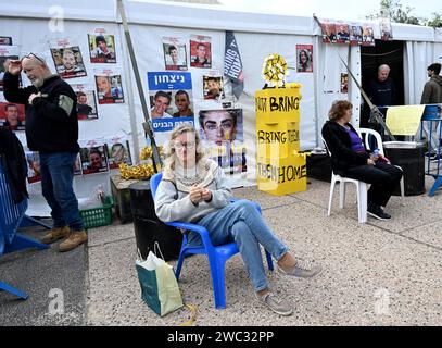 Tel Aviv, Israël. 13 janvier 2024. Les gens regardent des photos d’Israéliens toujours retenus en otage à Gaza par le Hamas sur la place des otages à tel Aviv le samedi 13 janvier 2024. Le 14 janvier, Israël marquera cent jours depuis le massacre du Hamas sur Israël et appellera à la libération des 136 otages encore détenus par le Hamas à Gaza. Photo de Debbie Hill/ crédit : UPI/Alamy Live News Banque D'Images