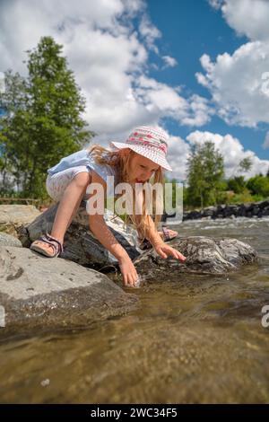 petite fille dans le paysage naturel d'une rivière de montagne, des pierres dans le canal, un ruisseau de montagne, la chaleur de l'été, peu d'eau, un jour clair Banque D'Images