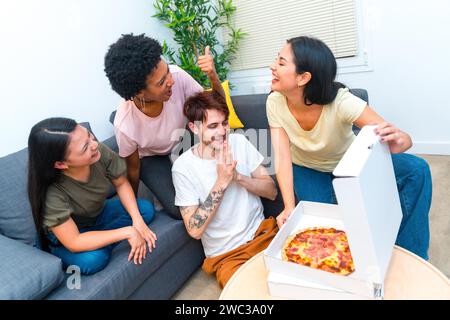 Vue de dessus d'un groupe d'amis affamés multi-ethniques ouvrant une boîte à pizza livrée Banque D'Images
