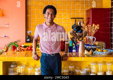 Sexe fluide jeune homme portant des vêtements de cross-dressing à la maison, LGBTQ et concepts de diversité - Hispanic non binaire portrait masculin dans un apartme coloré Banque D'Images