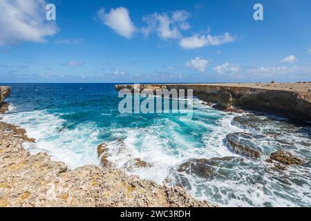 Vagues et mousse blanche se forment lorsque les vagues s'écrasent dans une baie rocheuse en fer à cheval avec de l'eau bleu clair et turquoise de l'océan Banque D'Images