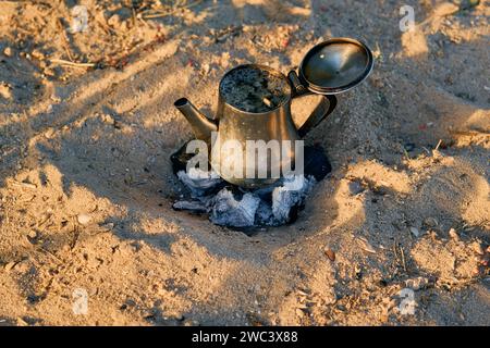 Thé marocain en plein air en préparation sur sable et charbon de bois Banque D'Images