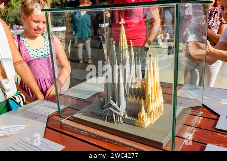 Guide touristique, touristes à l'extérieur devant la cathédrale de la Sagrada Família regardant un modèle montrant les étapes de construction de l'église, Barcelone Banque D'Images