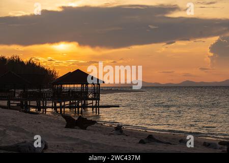 Sunrise silhouettes un quai et un belvédère sur une belle plage tropicale Banque D'Images